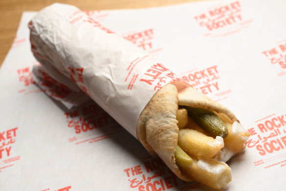 A wrap filled with hot chips, toum (garlic sauce) and pickles.