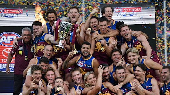 Brisbane Lions teammates celebrate with the premiership cup.