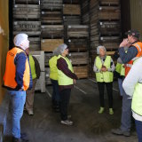 A tour group visits an apple packing shed. 