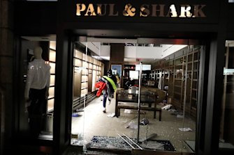 A man carries merchandise out of a store that was broken into in New York.