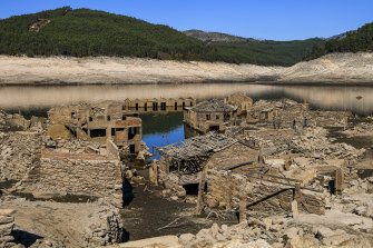 Tourists walk through the ruins of the partly submerged Aceredo village buildings as they emerge from the river Lima.