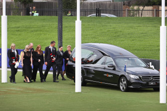 A hearse carries Shane Warne’s body around the St Kilda oval at Moorabbin, accompanied by children Brooke, Jackson and Summer, his parents Keith and Brigitte and his brother Jason.