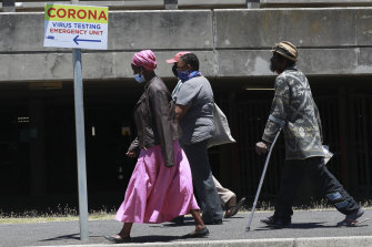 People pass a sign at Groote Schuur Hospital in Cape Town, South Africa, indicating a COVID testing station.