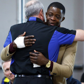 Shaw receiving a hug from Waffle House CEO Walt Ehmer during a press conference.