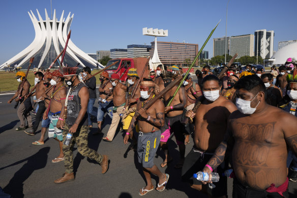Indigenous people march past the Brasilia Cathedral. Activists travelled to the capital to press for an end to illegal mining and logging on their land and oppose a bill they say would limit recognition of tribal lands.