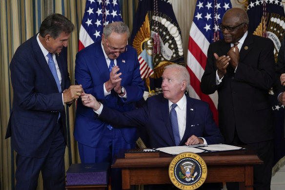 President Joe Biden hands the pen he used to sign the Democrats’ landmark climate change and health care bill to Senator Joe Manchin. Also pictured is Senate Majority Leader Chuck Schumer and Majority Whip James Clyburn.