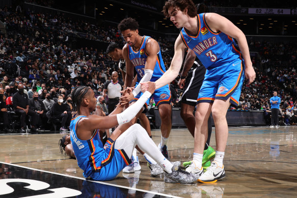 Aaron Wiggins #21 and Josh Giddey #3 help up teammate Shai Gilgeous-Alexander.