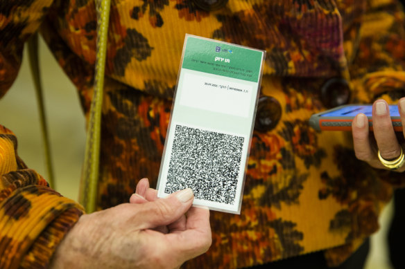 An Israeli woman presents a COVID-19 vaccination certificate named - or Green Pass - before entering a musical performance at Tel Aviv’s concert hall.