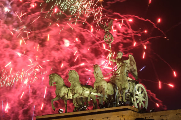 Fireworks crackle behind the Quadriga statue at the Brandenburg Gate.