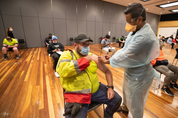 Warehouse worker Daniel Matcham rolls up his sleeve to get jabbed at a clinic in Hoppers Crossing.