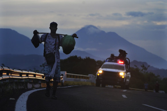 A migrant walks on the highway, followed by a Mexican Natio<em></em>nal Guard vehicle, towards the exit to Huixtla, Chiapas state, Mexico, in 2022.