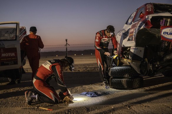 Fernando Alonso (centre) and co-crive Marc Coma (right) make repairs after their car rolled.