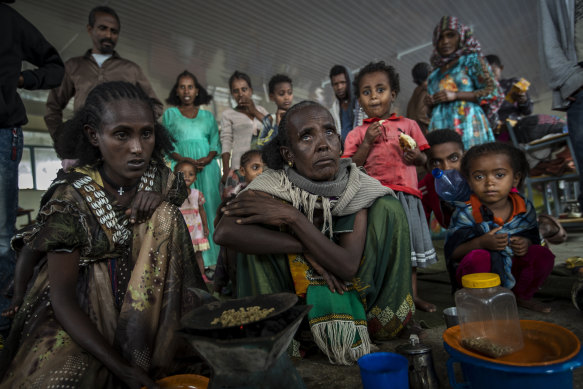 Tigrayan women Tarik, centre, and Meresaeta, left, roast coffee beans over a wood stove in a classroom in Mekele which became a makeshift home to thousands displaced by the conflict.