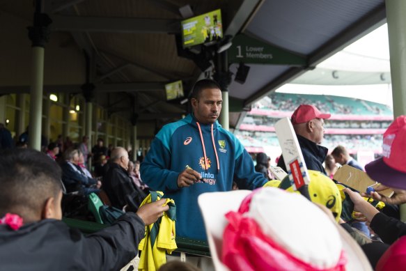 Usman Khawaja signs autographs waiting for play to start after a rain delay at the SCG on Saturday.