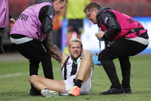 Jeremy Howe is helped up by Collingwood trainers after his final-term clash with Jacob Hopper.