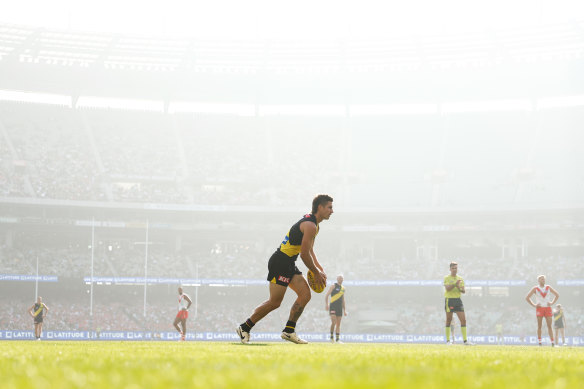 Richmond’s Liam Baker prepares to kick the ball as smoke haze hangs around the MCG on Sunday.