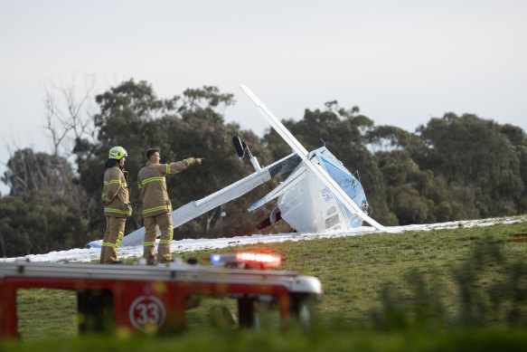 Firefighters inspect the crash scene near Moorabbin Airport on Tuesday.