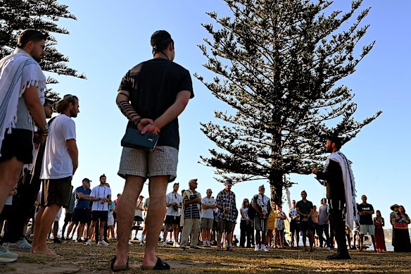 Rabbi Yossi Friedman (right) leads people in prayers at Archer Park on Friday.
