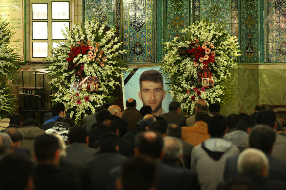 Men gather in front of a large photo of killed asylum seeker Reza Berati during the memorial service, held at the Al-Mahdi mosque in the Nabard neighbourhood in South East Tehran, Iran.