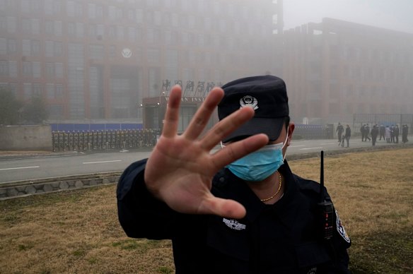 A security guard moves journalists away from the Wuhan Institute of Virology in 2021.