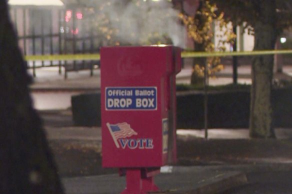 In this image made from a video provided by KGW8, authorities investigate the scene as smoke pours out of a ballot box on Monday.