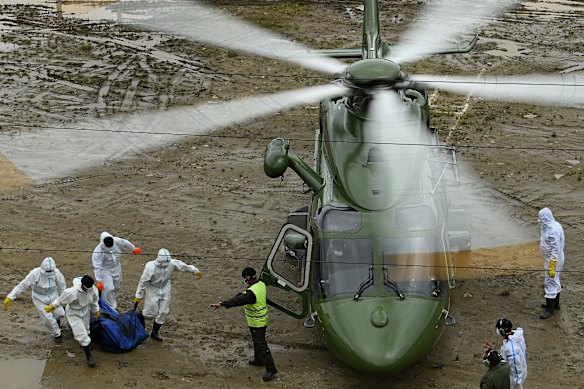 Nepalese police carry bodies to a helicopter for a flight to Chitwan, where hundreds of disaster victims are being buried.