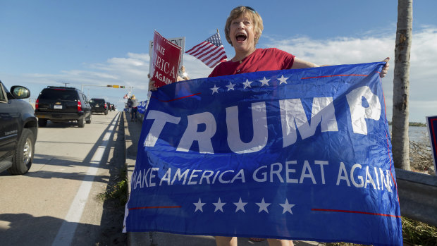 A supporter cheers for President Donald Trump as his motorcade passes by en route to Mar-a-Lago.