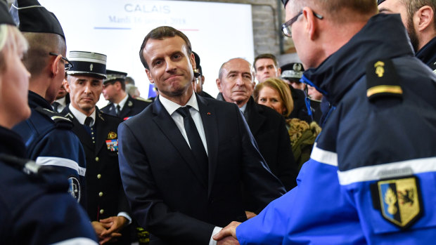 French President Emmanuel Macron shakes hands with members of police force during his visit to Calais, northern France.