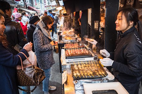 Street food being prepared at one of the many seafood stalls in the outer market of Tsukiji Fish Market. 