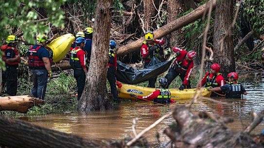 Firefighters from Ciudad Acuña, Mexico, load a body into a raft as they prepare for a water recovery along the Guadalupe River days after a flash flood swept through the area.