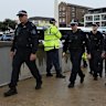 NSW Police walk toward Bondi Beach in February, three months after gunmen opened fire into a crowd of Jewish families from the footbridge.