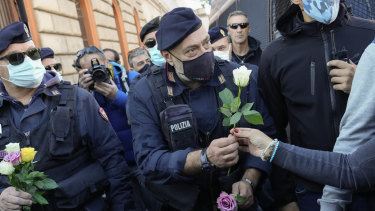 Demonstrators bring flowers to police officers at Rome’s Circus Maximus during a protest against a new anti COVID-19 measure.