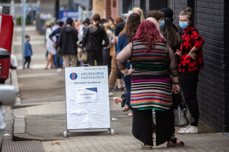 People queue outside the COVID-19 testing site on Alfred Street in North Melbourne on Sunday.