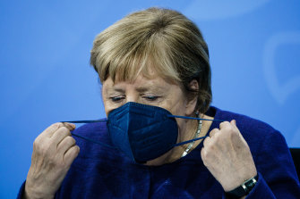 Chancellor Angela Merkel takes off her face mask during a press conference after meeting State Premiers and the acting Chancellor on the coronavirus situation.