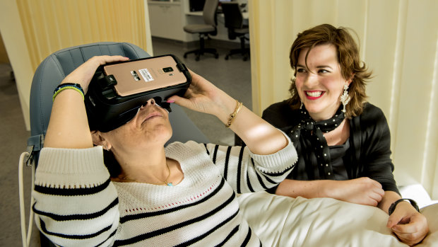 Prince of Wales Hospital is trialing VR therapy to help patients recover.
Pictured is Theodora Michalopoulos wearing a VR headset as former patient Stefanie Ammann looks on.