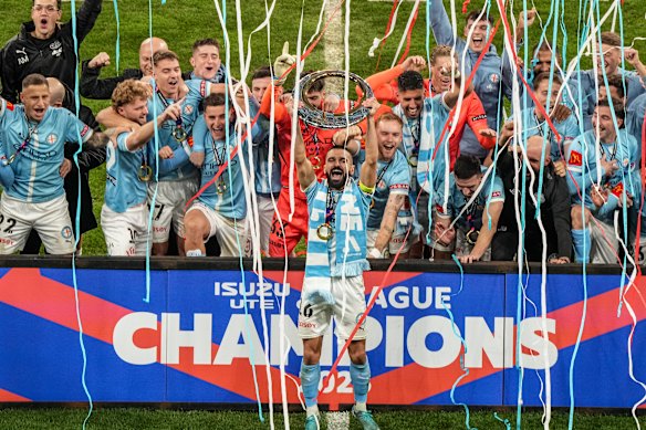 Aziz Behich of the City lifts the trophy as Melbourne City players celebrate after winning the A-League men grand final.
