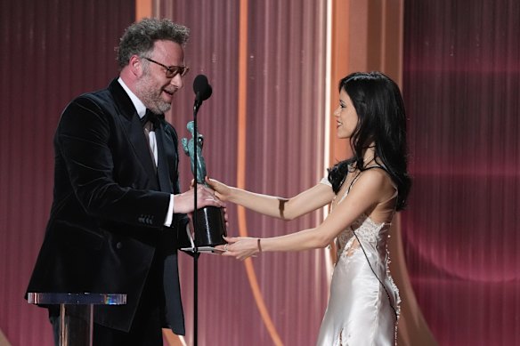 Jenna Ortega, right, presents the award for outstanding performance by a male actor in a comedy series to Seth Rogen.