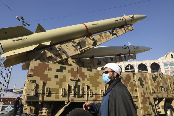 A cleric walks past Zolfaghar, top, and Dezful missiles displayed in a missile capabilities exhibition. 