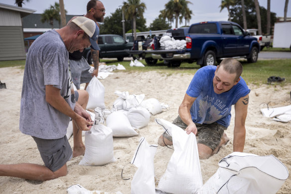 Trenton Spencer (right) fills sandbags for his neighbours in preparation for Hurricane Idalia.