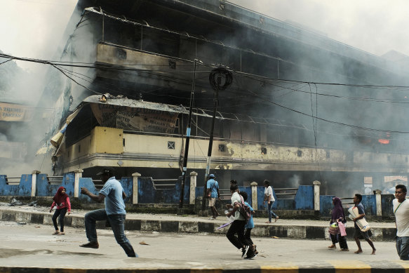 People flee as a local market in the West Papuan town of Fak Fak burns on August 21, 2019.