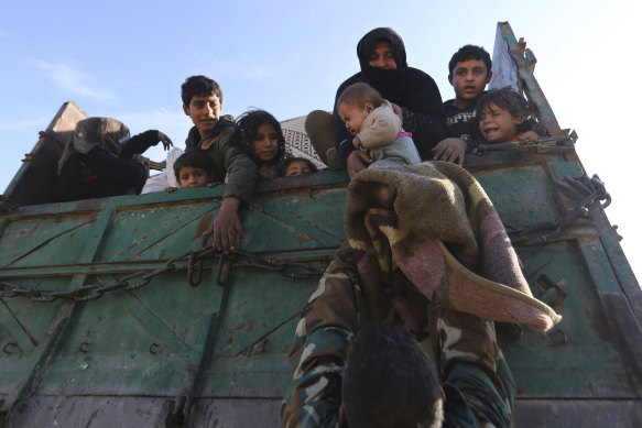 A baby is lifted onto a truck carrying civilians fleeing Maaret al-Numan, Syria, last week, ahead of the government offensive. 