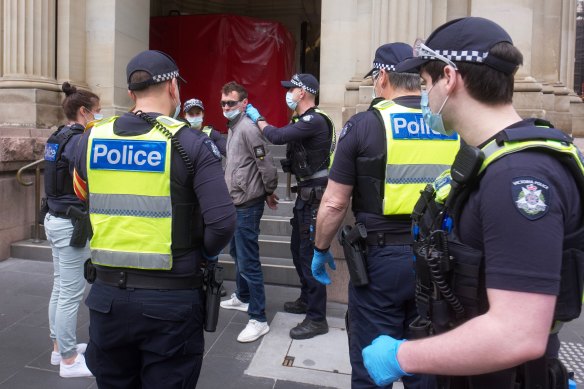 A man is detained by police in Melbourne on Friday.