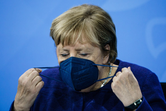 Chancellor Angela Merkel takes off her face mask during a press conference after meeting State Premiers and the acting Chancellor on the coronavirus situation.