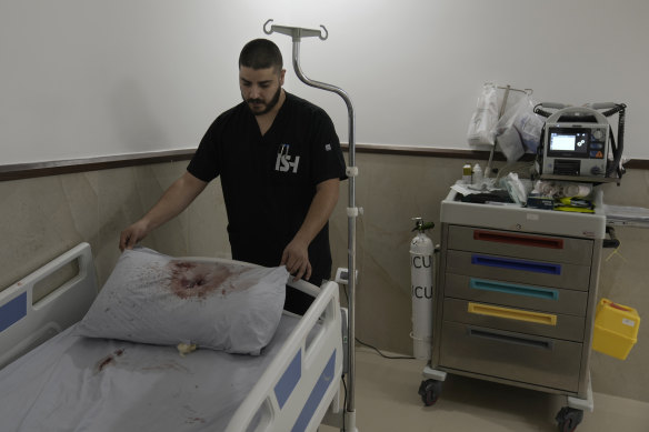 A staff member at Ibn Sina Hospital displays a blood-stained pillow.