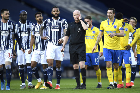 West Brom and Brighton players gather around referee Lee Mason as he makes the decision on whether to allow a goal to stand.