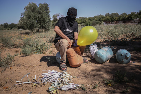 A masked Palestinian supporter of the Al-Nasir Salah Al-Din Brigades prepares incendiary balloons to launch across the border fence east of Gaza city towards Israel.