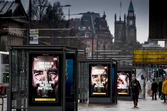 Members of the public walk past a government poster reminding people to socially distance and abide by the lockdown restrictions in Edinburgh, Scotland.