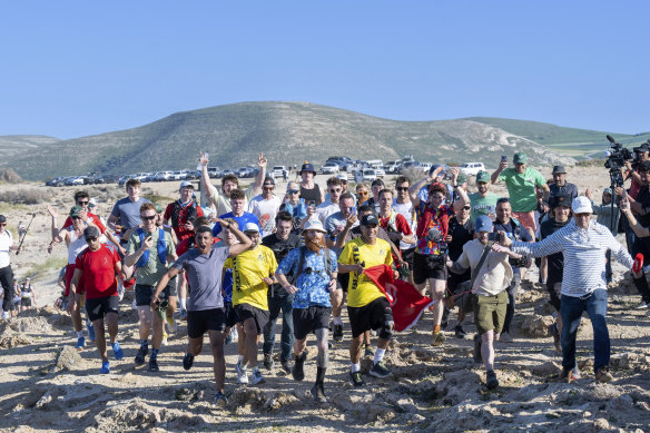 British runner Russ Cook (centre, blue shirt) arrives at the finish line in Ras Angela, the most northern point of the African continent, in Tunisia.