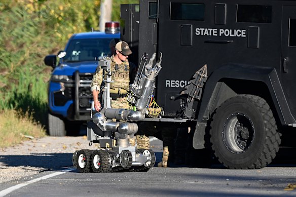 Um soldado do estado de Michigan com um robô perto da casa do suspeito.