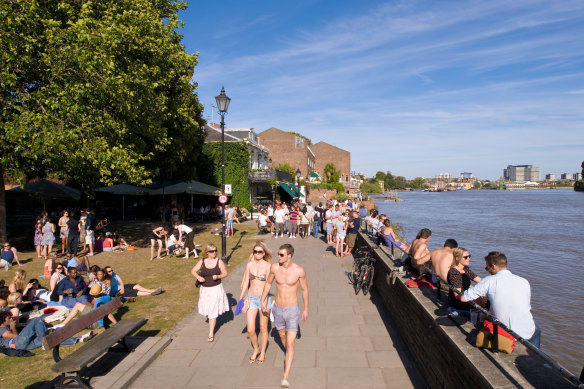 Sun’s out, guns out: People relax alongside the Thames in a rare show of sunshine.